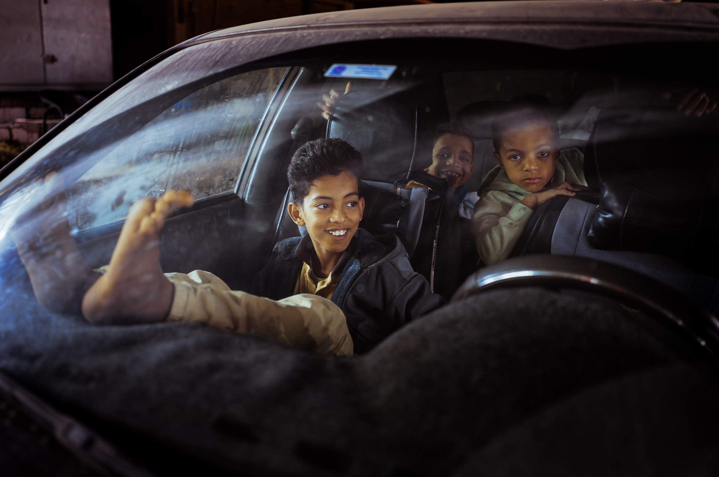 Cinematic night portrait through red-lit window, color street photography by Evangelos Tzemis